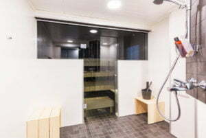 Saunan upea lasitus. Lasiovi, joka kiinni lasiseinässä ja kiviseinässä.