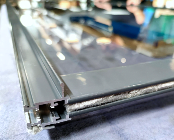 Harmaa terassin liukuovi harmaalla lasilla Vantaan tuotantotilan kokoonpanopöydällä